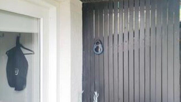 Une pièce avec une porte en bois, un manteau accroché au mur et un petit panneau circulaire.
