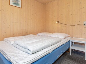 A single bed with a white duvet and pillows, a bedside table, and a wall-mounted light fixture. - 6 Person Holiday Home in Logstor (Logstor)