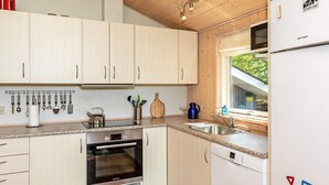 A modern kitchen with white cabinets, stainless steel appliances, and a window providing natural light. - 6 Person Holiday Home in Logstor (Logstor)