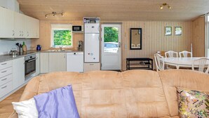 A cozy living area with a sofa, a dining table, and a kitchen with wooden cabinets and appliances. - 6 Person Holiday Home in Logstor (Logstor)