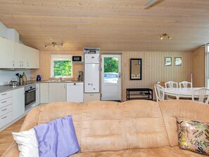 A cozy living area with a sofa, a dining table, and a kitchen with wooden cabinets and appliances. - 6 Person Holiday Home in Logstor (Logstor)