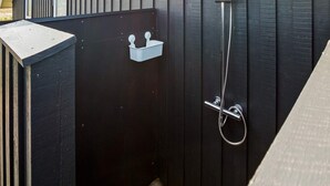 A black exterior wall with a metal shower head and hose, a white outdoor light fixture, and a small white storage box. - 8 Person Holiday Home in Harboore (Harboore)
