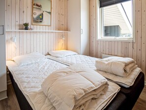 Une chambre avec deux lits, une fenêtre, un miroir et une étagère sur laquelle est posé un modèle de voiture.