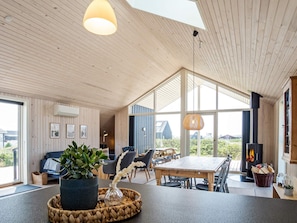 A spacious living area with a large wooden table, comfortable seating, and a fireplace. - 8 Person Holiday Home in Harboore (Harboore)
