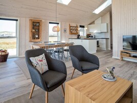 Un espacio moderno para vivir con comedor, cocina y zona de estar, televisión y objetos decorativos.
