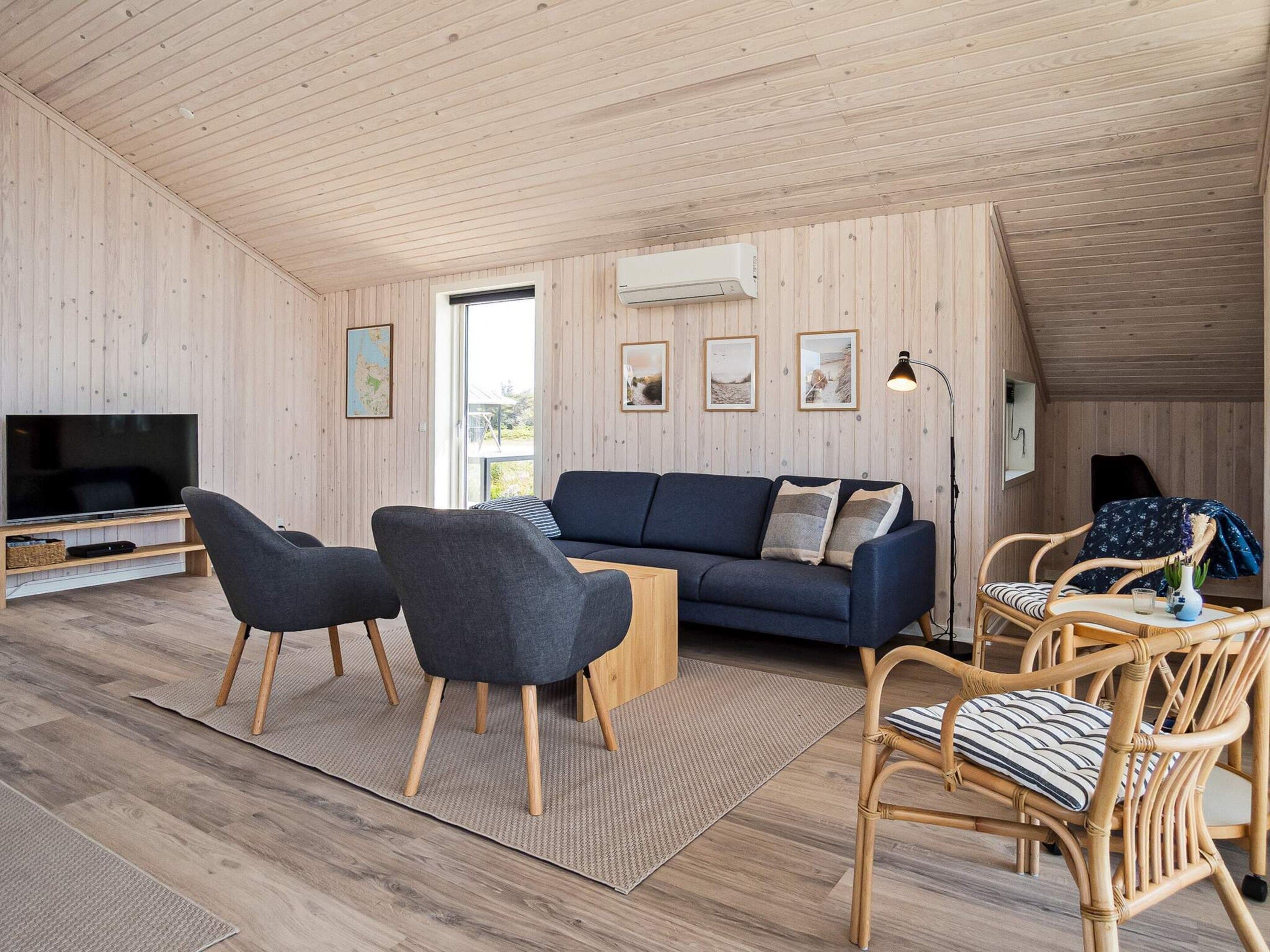A modern living room with a sofa, chairs, a TV, and a dining area.