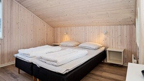 A single bed with a black frame and white bedding, a bedside table, and a wall-mounted lamp. - 8 Person Holiday Home in Harboore (Harboore)
