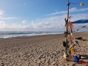 Una platja amb una escultura feta de diversos objectes i restes.