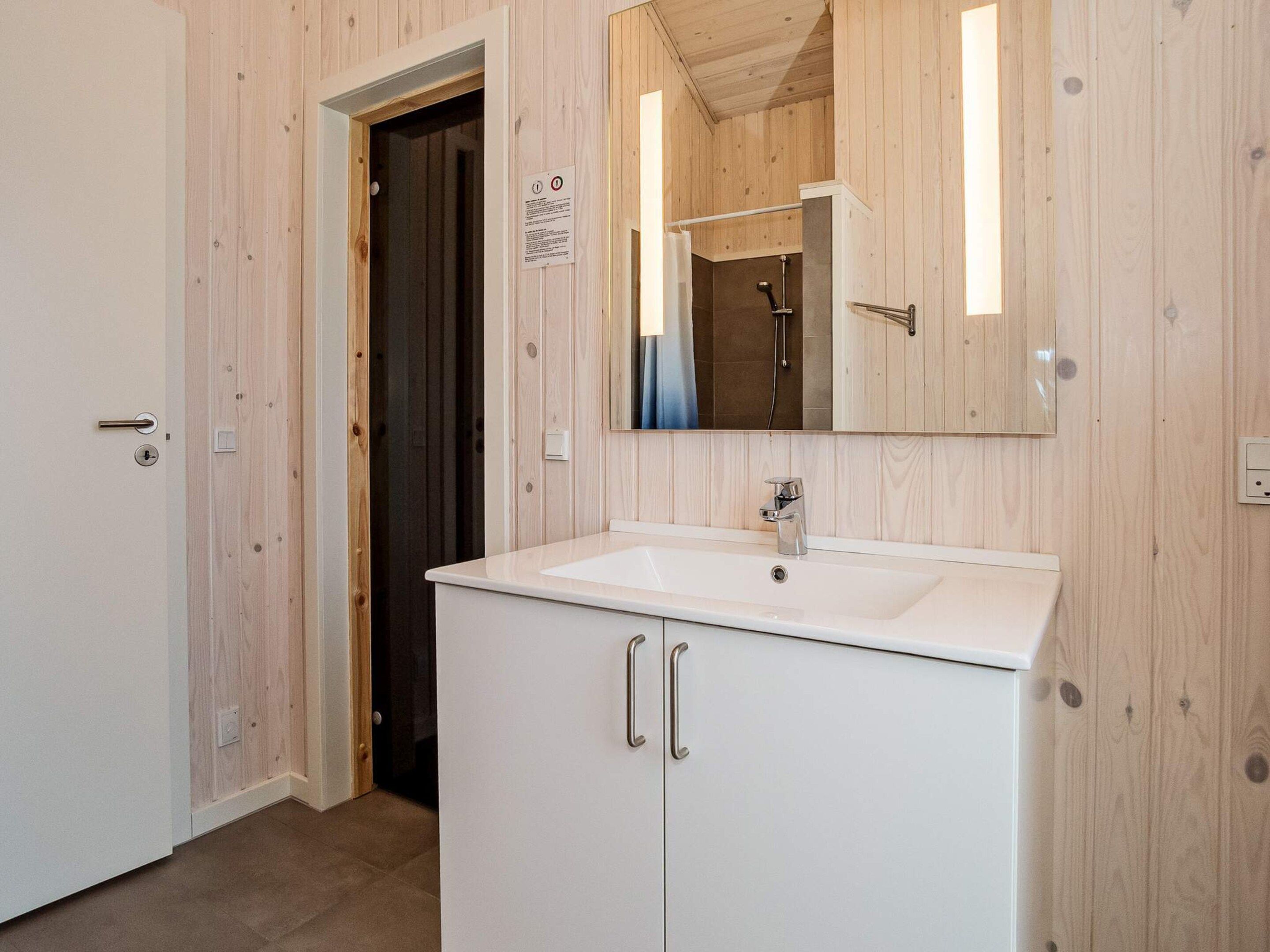 Ein Badezimmer mit einem weißen Waschbecken, einem Spiegel und einer Dusche.