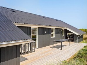 A modern building with a flat roof, large windows, and a wooden deck. - 8 Person Holiday Home in Harboore (Harboore)