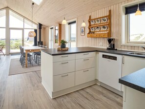 Une cuisine moderne avec des meubles blancs, un plan de travail noir et un pare-feu en bois.