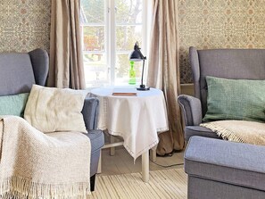 A cozy living room with two armchairs, a small table with a lamp, and a view through a window. - 4 Star Holiday Home in Mariestad (Mariestad)