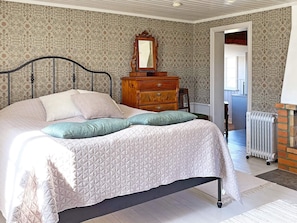 A bedroom with a bed, dresser, mirror, and radiator. - 4 Star Holiday Home in Mariestad (Mariestad)