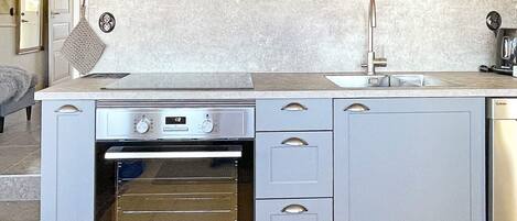A compact kitchen with a built-in oven, a sink, and a stove.