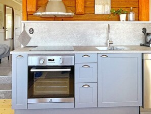 A compact kitchen with a built-in oven, a sink, and a stove. - 4 Star Holiday Home in Mariestad (Mariestad)
