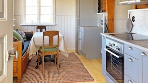 A compact kitchen with a dining area, wooden cabinets, and a built-in oven. - 4 Star Holiday Home in Mariestad (Mariestad)