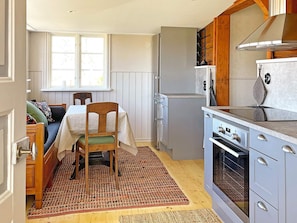 A compact kitchen with a dining area, wooden cabinets, and a built-in oven. - 4 Star Holiday Home in Mariestad (Mariestad)