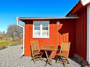 A red wooden building with a window and two wooden chairs and a table outside. - 4 Star Holiday Home in Mariestad (Mariestad)