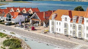 A coastal town with traditional buildings, a road, and a body of water. - 4 Person Holiday Home in Hejls (Hejls)