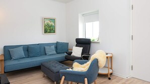 Un salon comprenant un canapé, un pouf, un fauteuil et une petite table ronde.