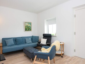 A living room with a sofa, ottoman, armchair, and a small round table. - 4 Person Holiday Home in Hejls (Hejls)