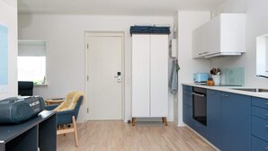 Une cuisine de taille réduite avec un plancher en bois, une chaise bleue, une porte blanche et un meuble bleu.