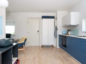 A compact kitchen with a wooden floor, a blue chair, a white door, and a blue cabinet. - 4 Person Holiday Home in Hejls (Hejls)
