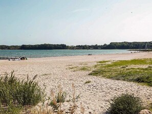 A beach with a sandy shore, a dock, and a picnic table. - 4 Person Holiday Home in Hejls (Hejls)