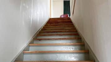 Eine Treppe mit Holzstufen und einem Geländer, die zu einem Raum mit einem grünen Vorhang führt.