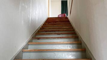 Een trap met houten treden en een leuning, die leidt naar een ruimte met een groen gordijn.