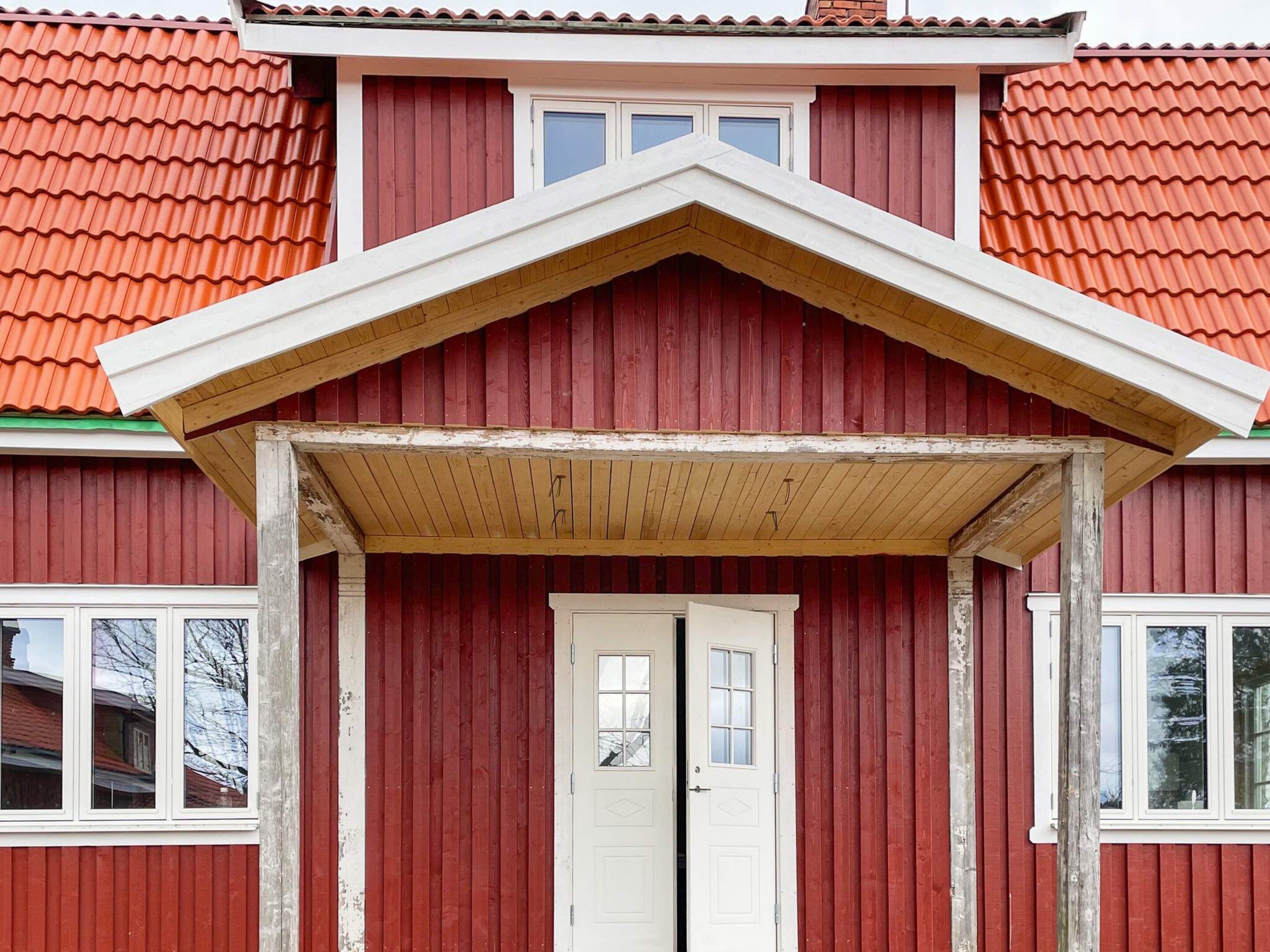 A red building with a white door and a small porch.