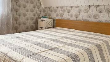 Un dormitorio con una cama, una mesita de noche y una pared decorada con un estampado de árbol.
