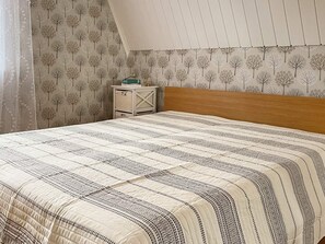 Une chambre à coucher avec un lit, une table de chevet et un mur orné d’un motif d’arbre.