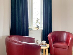 A room with two red leather chairs, a small round table with two cups and a book, and a window with curtains. - 4 Star Holiday Home in Vastra Amtervik (Vastra Amtervik)