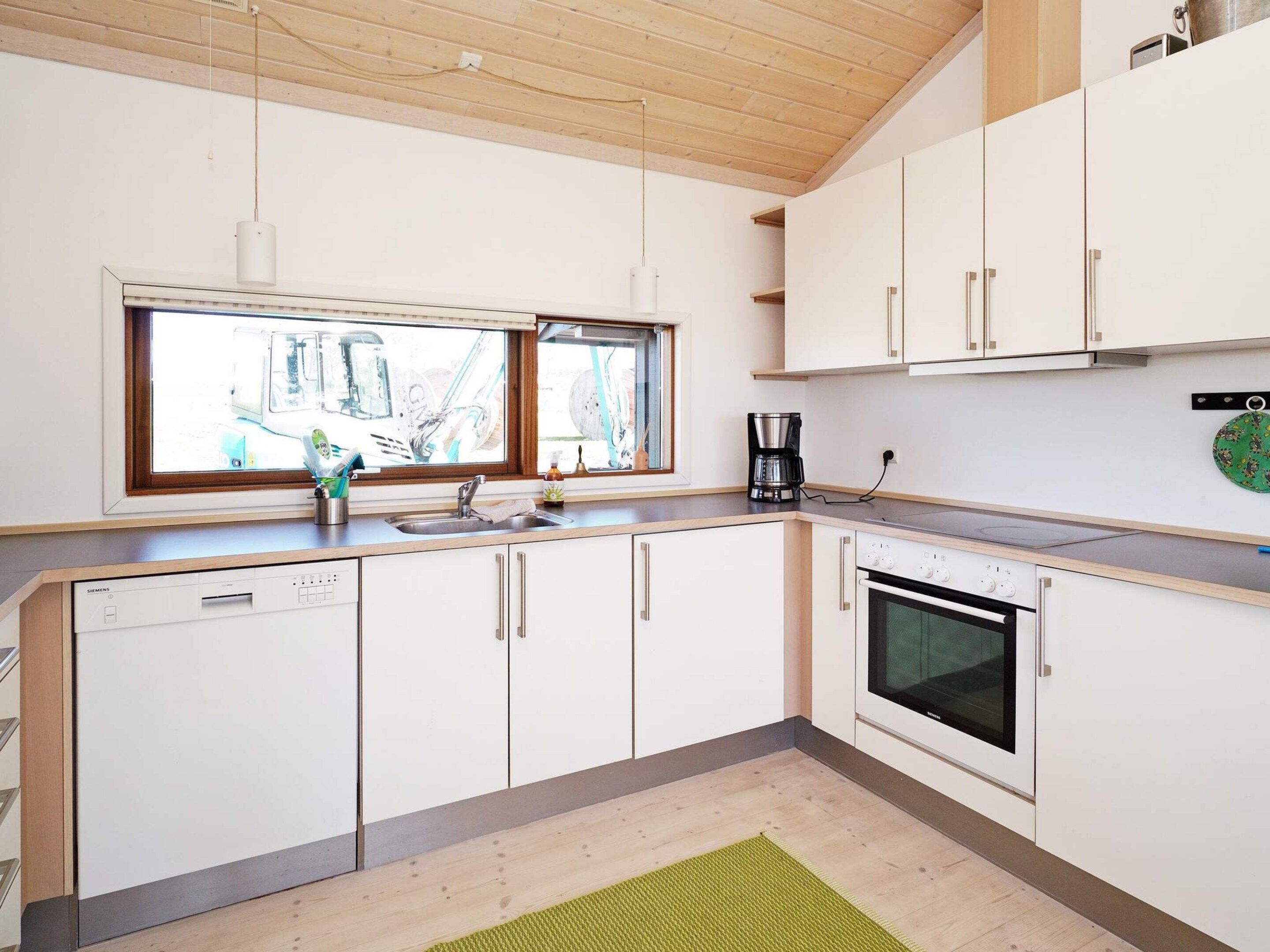 A modern kitchen with white cabinetry, a built-in oven, and a window above the sink.
