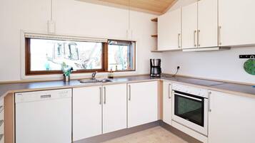 A modern kitchen with white cabinetry, a built-in oven, and a window above the sink.