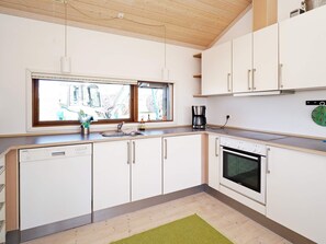 A modern kitchen with white cabinetry, a built-in oven, and a window above the sink. - 8 Person Holiday Home in Store Fuglede (Store Fuglede)