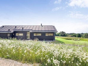 A two-story house with a dark exterior, large windows, and a sloped roof. - 8 Person Holiday Home in Store Fuglede (Store Fuglede)