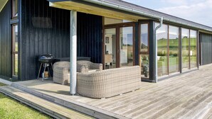Une maison moderne dotée d’un patio couvert, de grandes fenêtres et d’une cheminée.