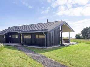 A modern two-story house with a dark exterior, a covered porch, and a gravel pathway leading to the entrance. - 8 Person Holiday Home in Store Fuglede (Store Fuglede)