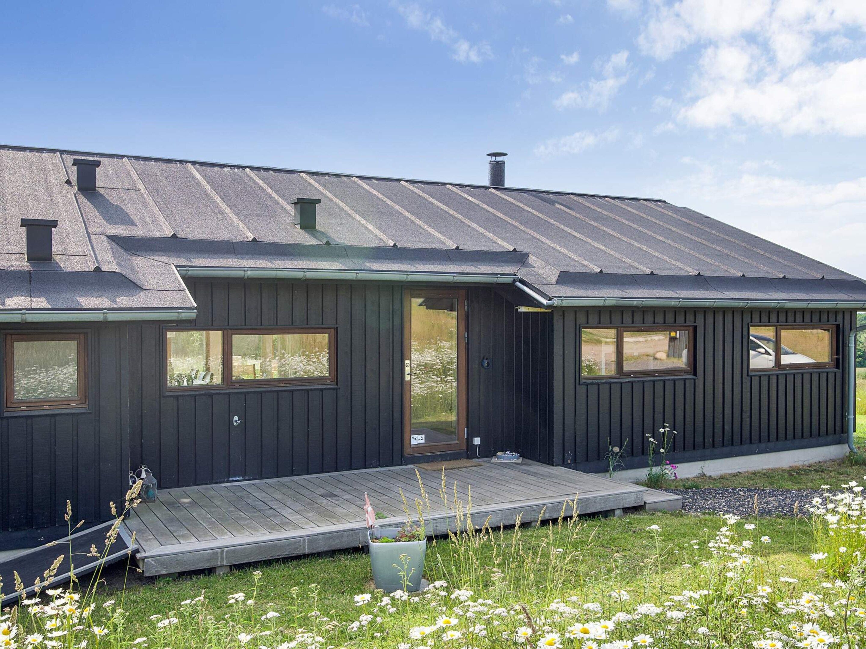 A modern house with a dark exterior, a sloped roof, and a front porch.