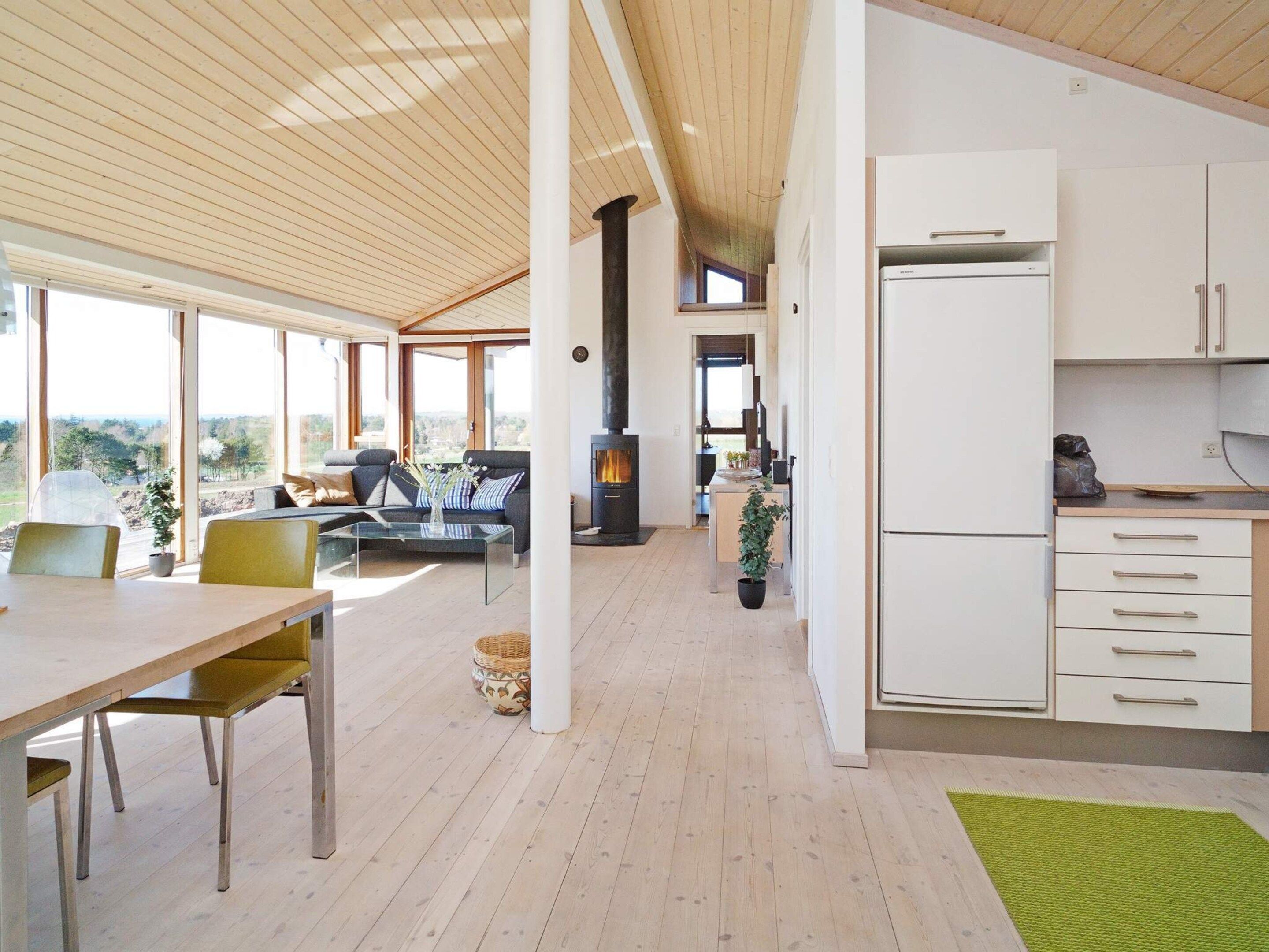 A modern kitchen with white cabinets, a built-in stove, and a dining area with a table and chairs.