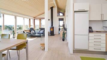 A modern kitchen with white cabinets, a built-in stove, and a dining area with a table and chairs.