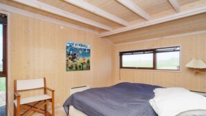 Una habitación con una cama, una silla, una ventana y un cartel en la pared.