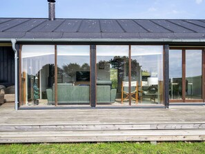 Una casa moderna con un'ampia porta scorrevole in vetro, un patio in legno e un camino.