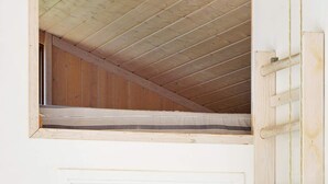 Una habitación con zona de descanso elevada, una puerta de madera y un ventanal pequeño.