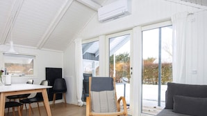 Un soggiorno moderno con zona pranzo, un divano grigio, una sedia di legno e un tavolo con sedie.
