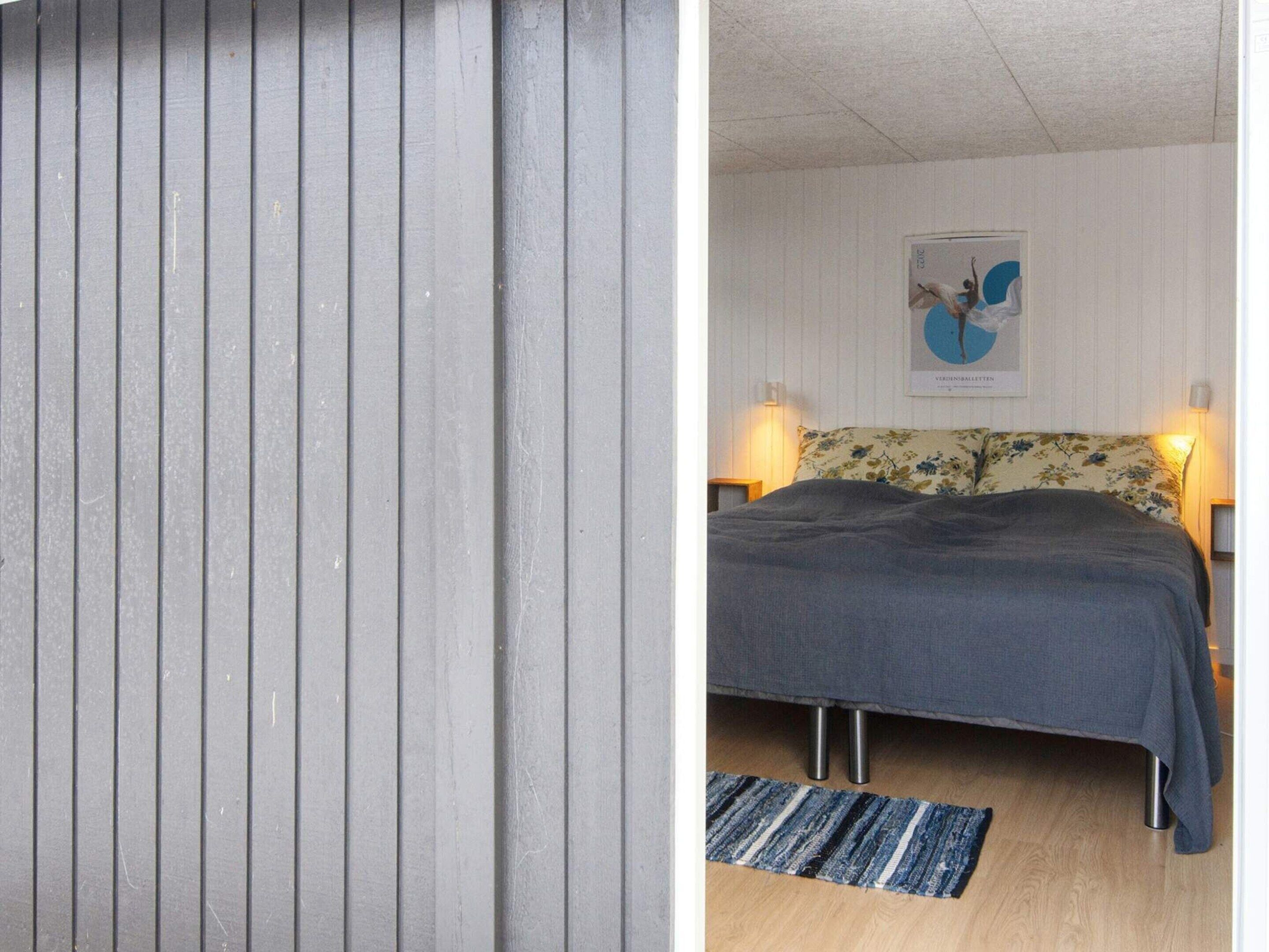 A bedroom with a bed, a wall-mounted painting, and a bedside lamp.