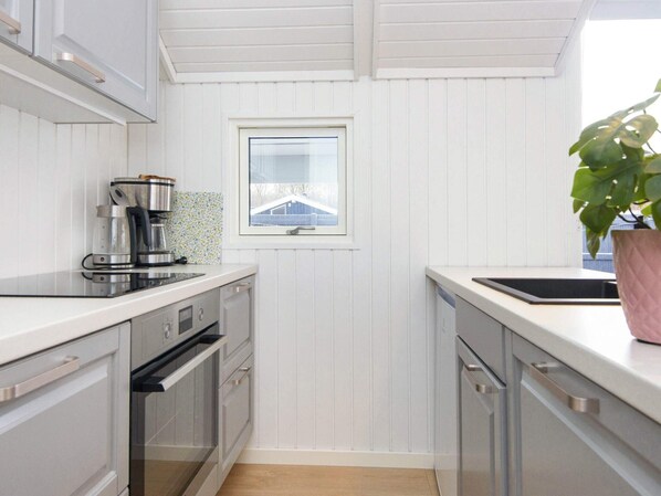 A modern kitchen with white cabinetry, a window, and a potted plant. - 6 Person Holiday Home in Juelsminde (Horsens)