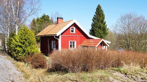 A red house with a sloped roof, surrounded by trees and shrubs. - 4 Person Holiday Home in Hedekas (Hedekas)